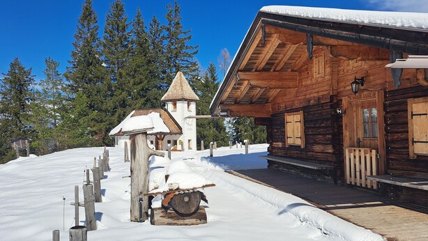 Eine Holzhütte mit schneebedecktem Dach und einem kleinen, turmartigen Aufbau.