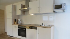 Eine moderne Küche mit weißen Schränken, einem Backofen, einer Mikrowelle und einer Kaffeemaschine.