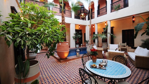 A courtyard with a round table, wicker furniture, and potted plants.