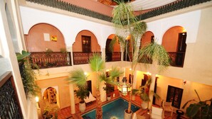 A courtyard with a pool, potted plants, and seating areas.
