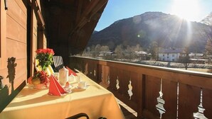 En balkon med et bord dækket til the, med udsigt over et bjergrigt landskab.