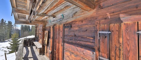 A wooden cabin with a porch, a metal door, and a window.