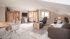 Una sala de estar amplia con comedor, un sofá, un sillón reclinable y un televisor.