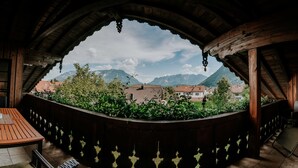 Un balcón de madera con vistas a montañas y casas.