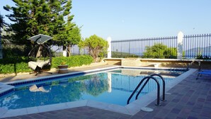 Una piscina con borde de azulejos, una escalera de metal y una cerca blanca.