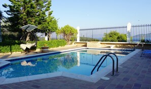 Alberca al aire libre, sombrillas en la alberca y camastros