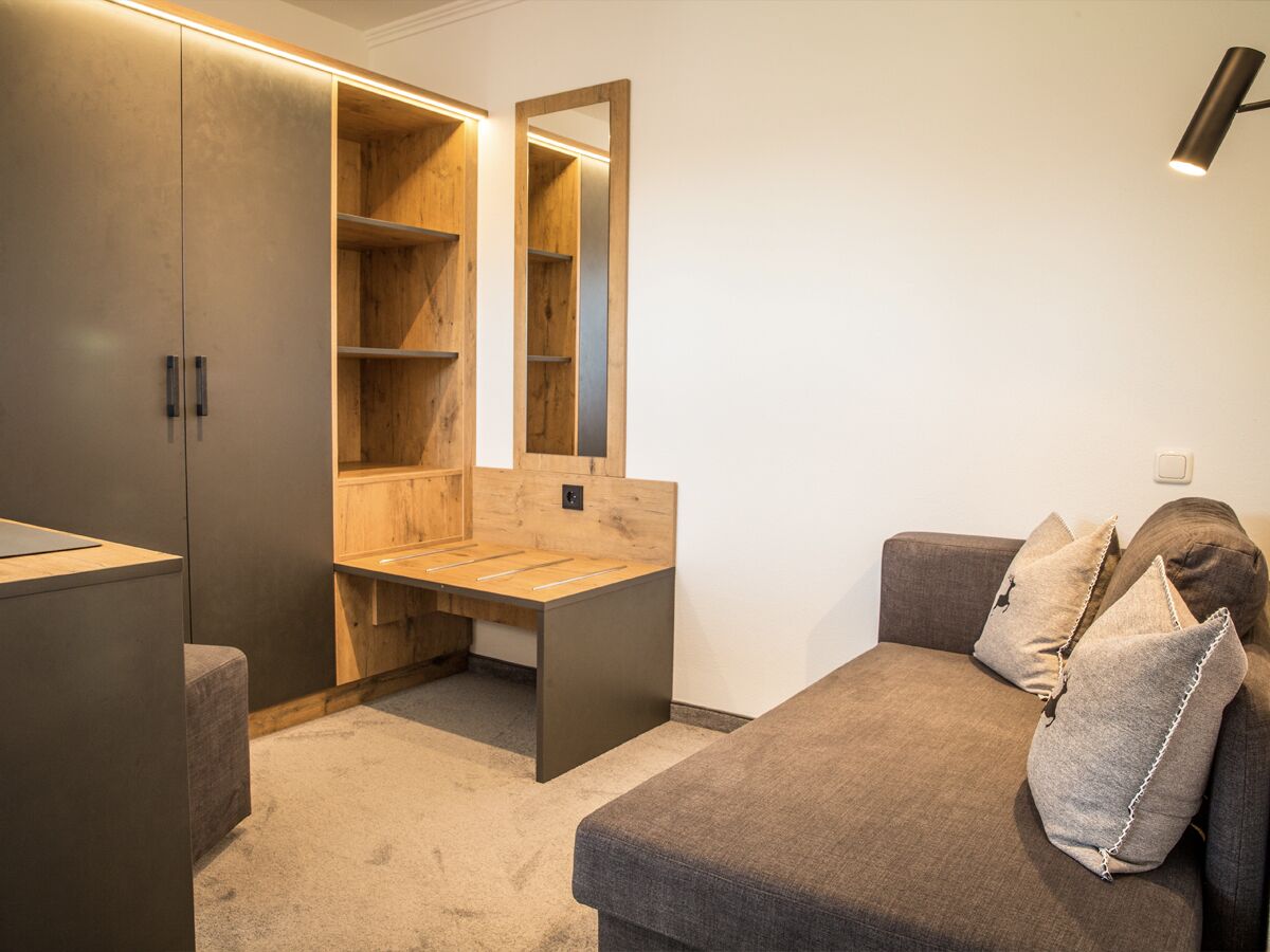 Una habitación pequeña con cama, escritorio y armario.