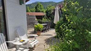 Un patio con una mesa y sillas, una planta en maceta y una valla de madera al fondo.