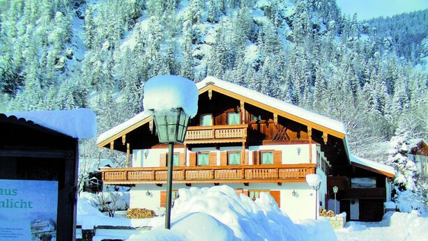 A wooden chalet with multiple balconies, surrounded by snow-covered trees. - (07)Zwei-Raum-Ferienwohnung, 28qm, 2-4 Personen, Extra-Schlafzimer, separate Küche, Balkon (Reit im Winkl)