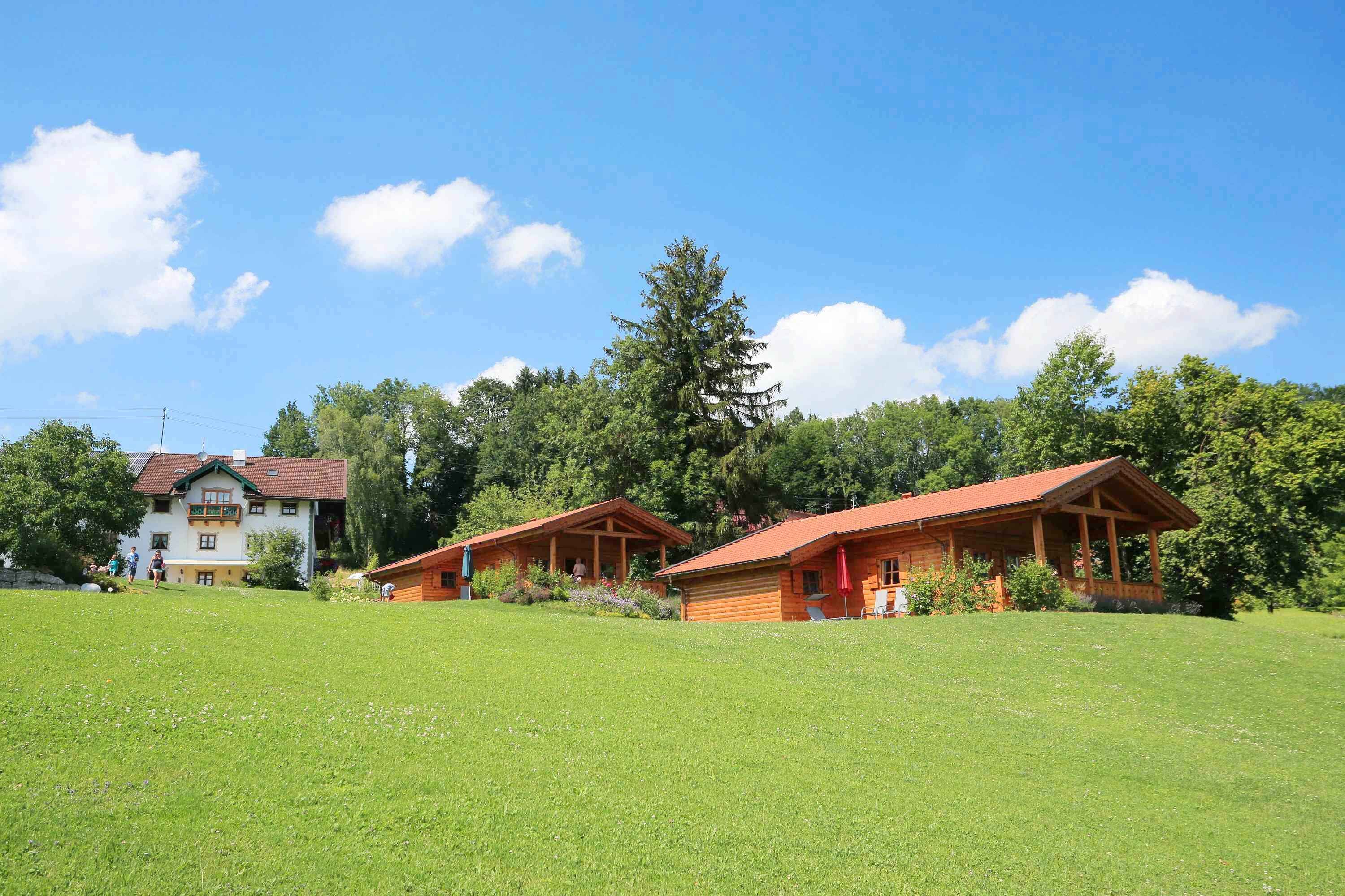 Eine Lodge mit zwei Holzhäuschen, einem großen Haus und einem grünen Feld.
