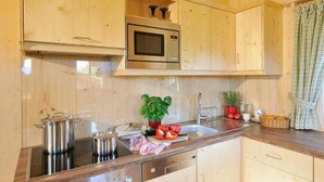 Eine Küche mit Holzausstattung, einer Edelstahl-Mikrowelle, einem Herd und einem Spülbecken.