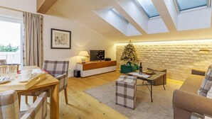 A cozy living room with a high ceiling, skylights, a fireplace, and a Christmas tree. - Vakantiewoning Unternberg (Reit im Winkl)