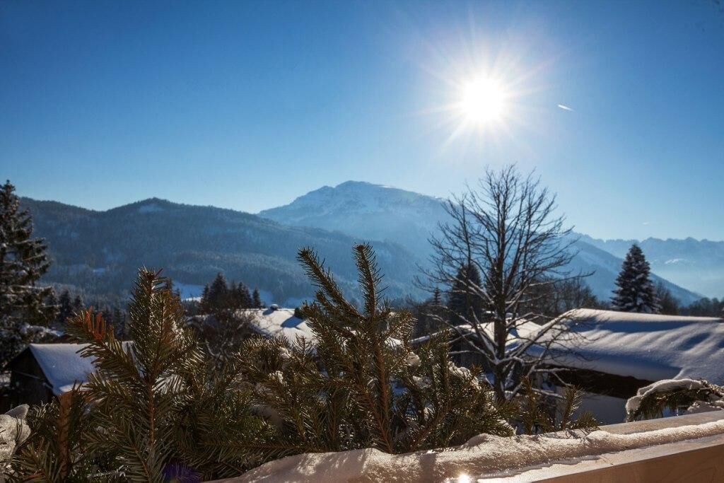A snowy mountain landscape with a clear sky and the sun shining.