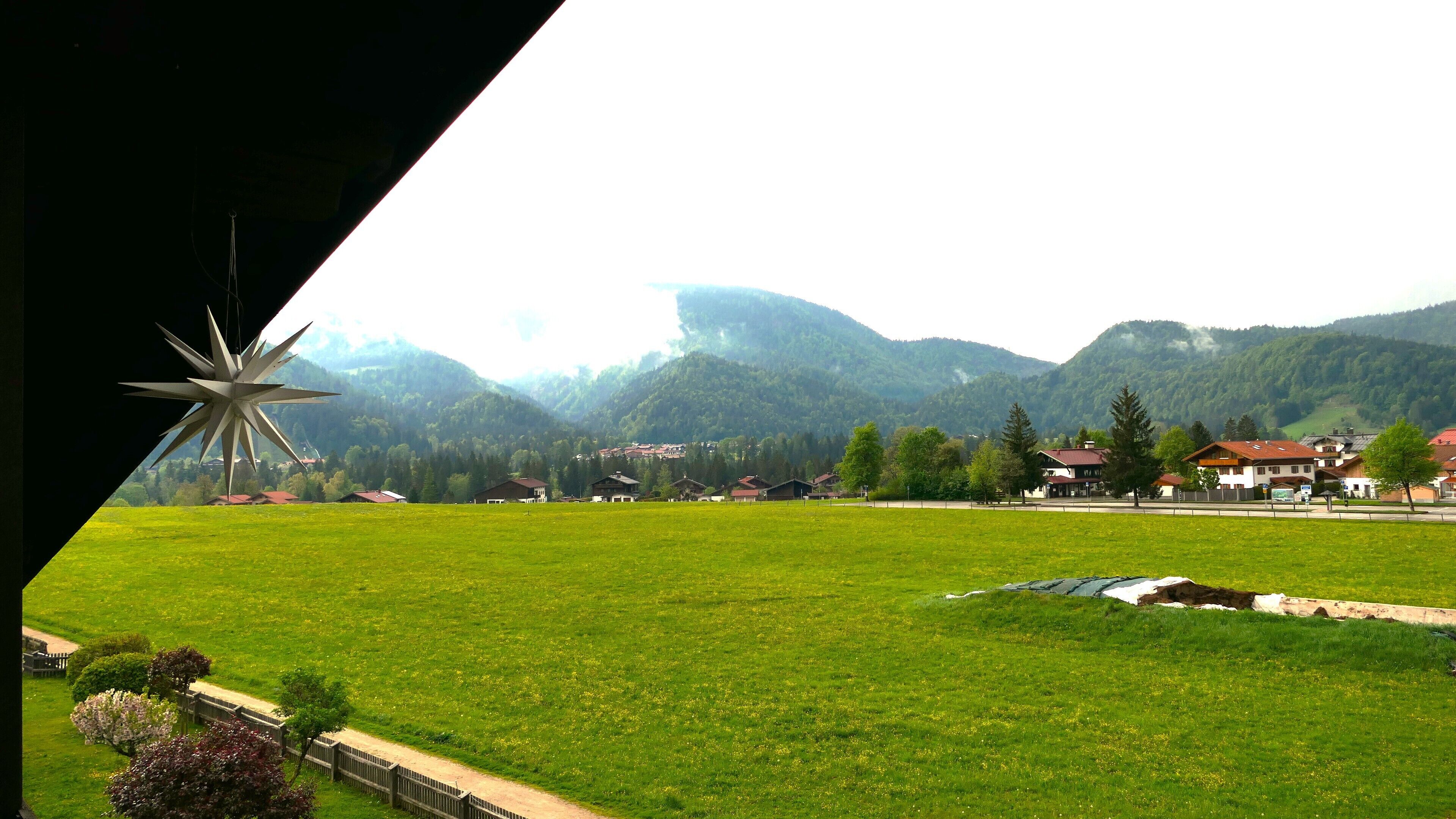 Un paysage rural avec un moulin à vent, des maisons et des montagnes.