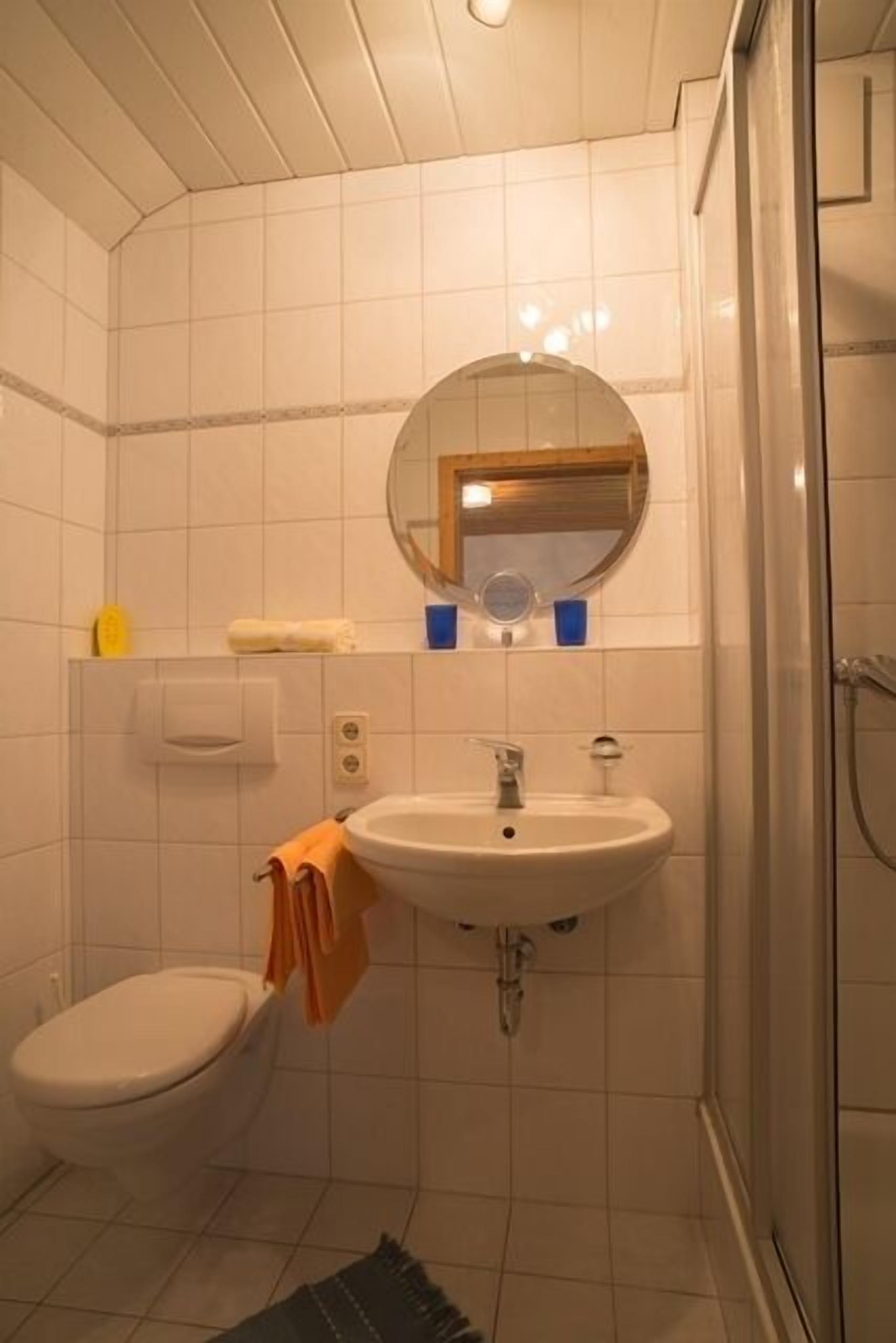 Et badeværelse med toilet, vask og spejl.