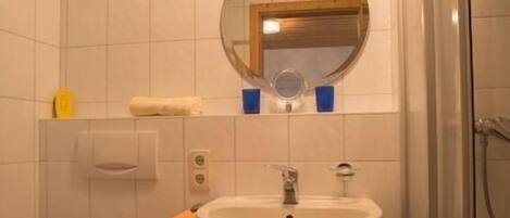 Et badeværelse med toilet, vask og spejl.