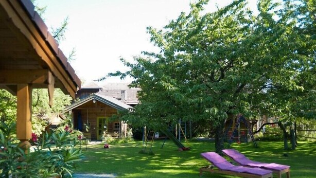 A wooden house with a covered porch, a grassy yard, and a swing set. - Vacation apartment no. 2, 30 sqm, 1 bedroom, terrace, 4 stars, 3 pers. (Anger)