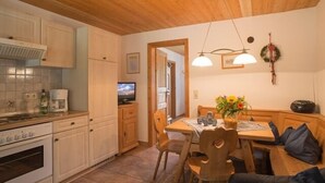 A cozy kitchen with wooden cabinets, a built-in oven, and a dining area with a table and chairs. - Vacation apartment no. 2, 30 sqm, 1 bedroom, terrace, 4 stars, 3 pers. (Anger)