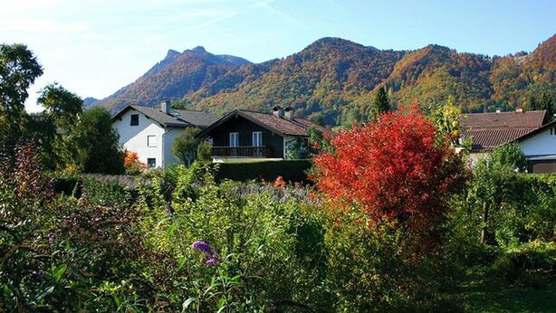 A rural setting with houses surrounded by lush greenery and mountains in the background. - Ferienwohnung 50 qm, extra Schlafzimmer im Erdgeschoss° (Aschau im Chiemgau)