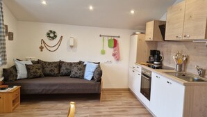 A compact living space with a sofa, kitchenette, and wooden cabinets.