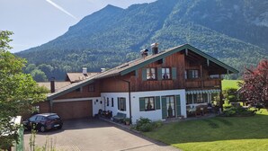 A wooden chalet with a sloped roof, a covered porch, and a view of a mountain.
