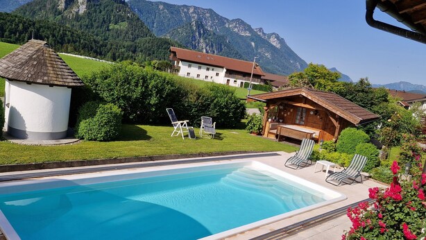 A swimming pool with lounge chairs, a small gazebo, and a mountain backdrop.