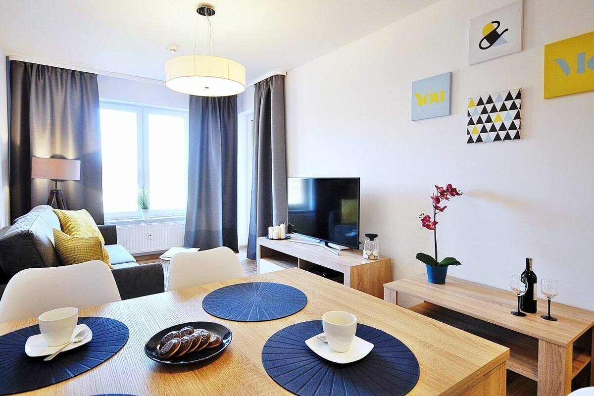 Ein modernes Hotelzimmer mit Essbereich, einer Couch, einem Fernseher und Kunstwerken an der Wand.