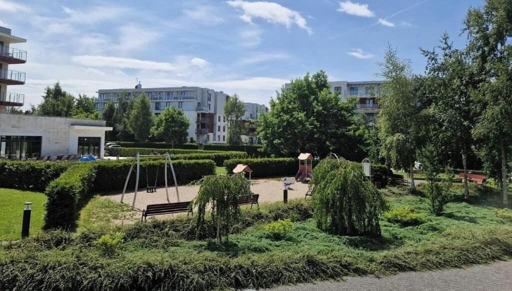 Un parque con columpios, bancos y un área de juegos.