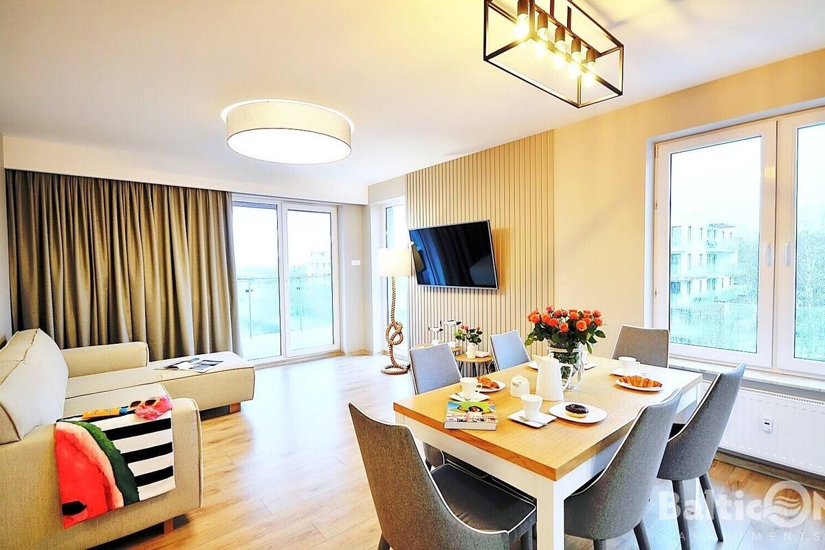 Ein modernes Hotelzimmer mit Essbereich, einer Couch, einem Fernseher und großen Fenstern.
