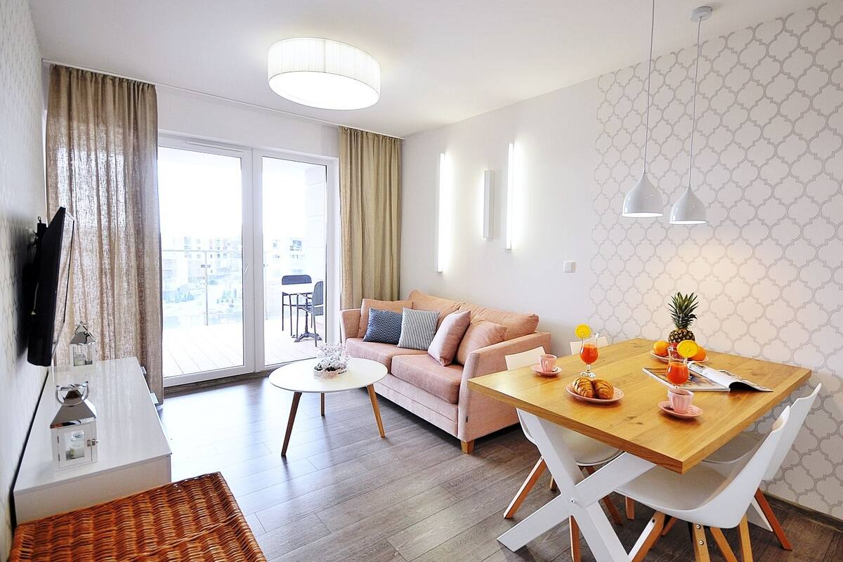Ein modernes Wohnzimmer mit einer Couch, einem Esstisch und einem an der Wand montierten Fernseher.