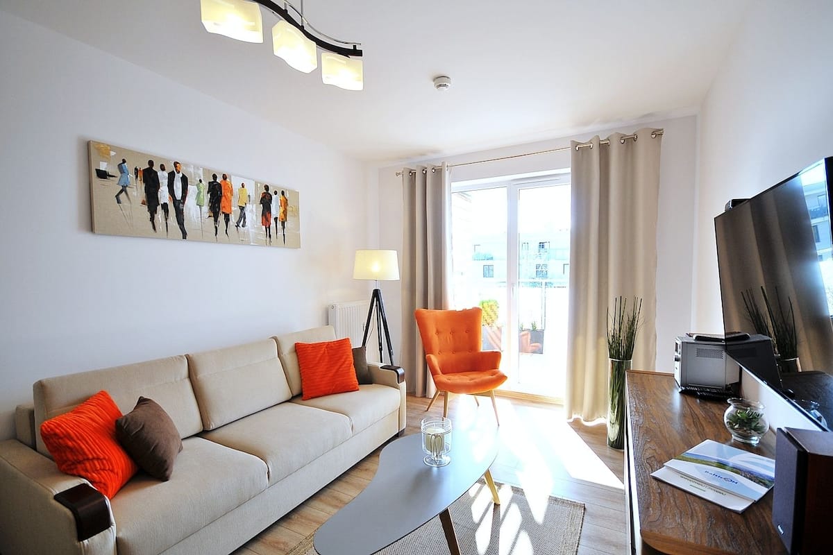 Ein modernes Wohnzimmer mit Sofa, Sessel, Couchtisch und Flachbildfernseher.