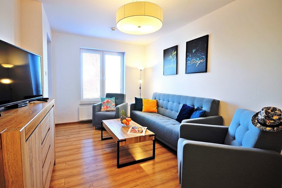Ein modernes Wohnzimmer mit Flachbildfernseher, einer Couch, einem Couchtisch und einer Holzkommode.