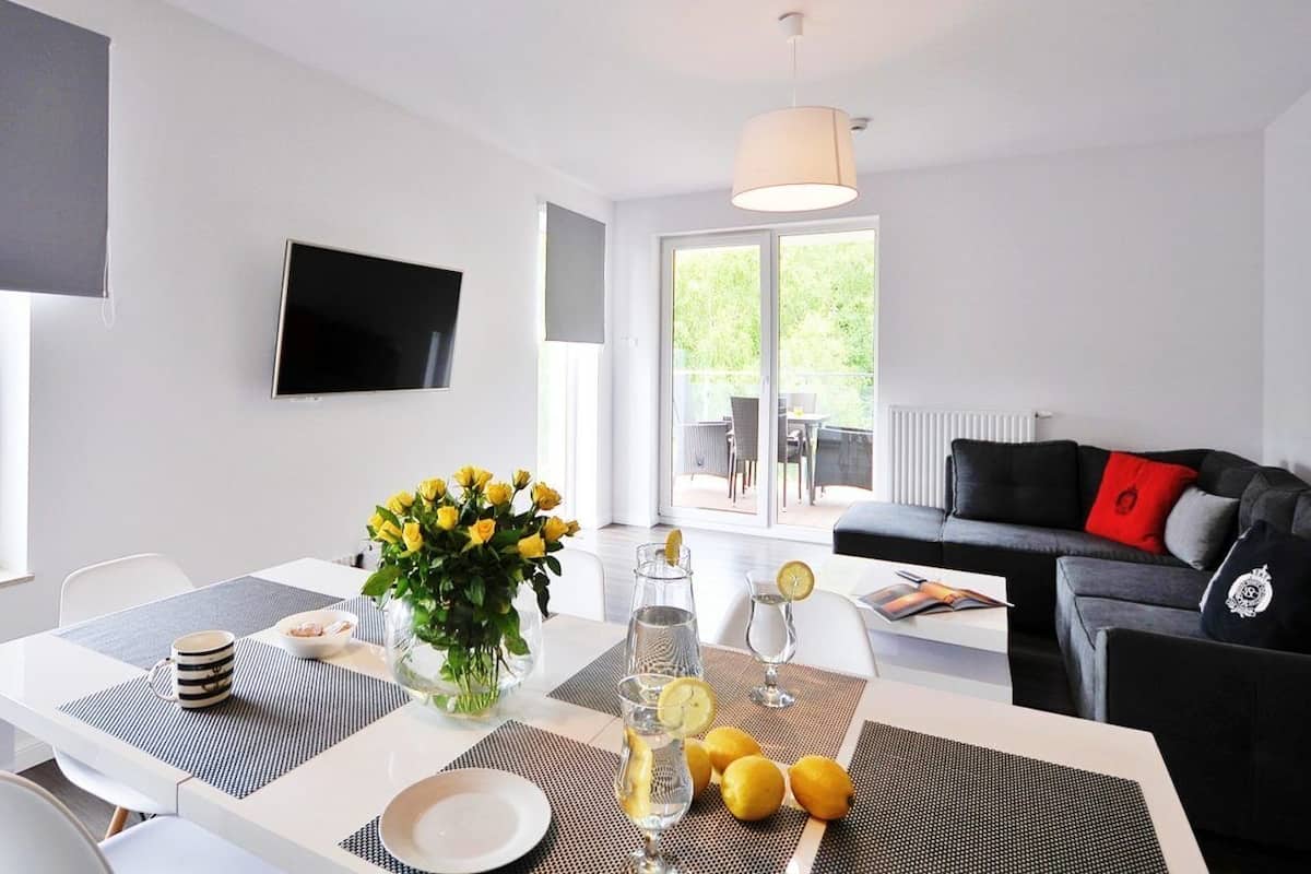 Ein modernes Wohnzimmer mit Essbereich, einem Wand-Fernseher und einer roten Sitzsofa-Polsterung.