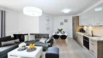 A modern living room with a sofa, coffee table, and dining area.