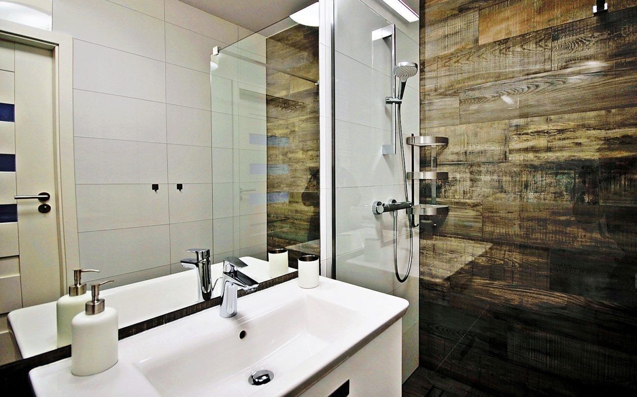 A modern bathroom with a large mirror, a white sink, and a shower area.