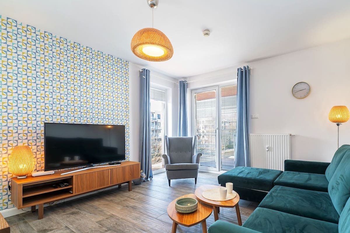 Ein modernes Wohnzimmer mit Fernseher, Sofa und einer Wand mit Muster.