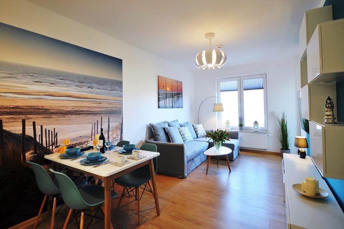 Ein modernes Wohnzimmer mit Essbereich, einer Couch, einem Couchtisch und einem Gemälde von einem Sonnenuntergang.