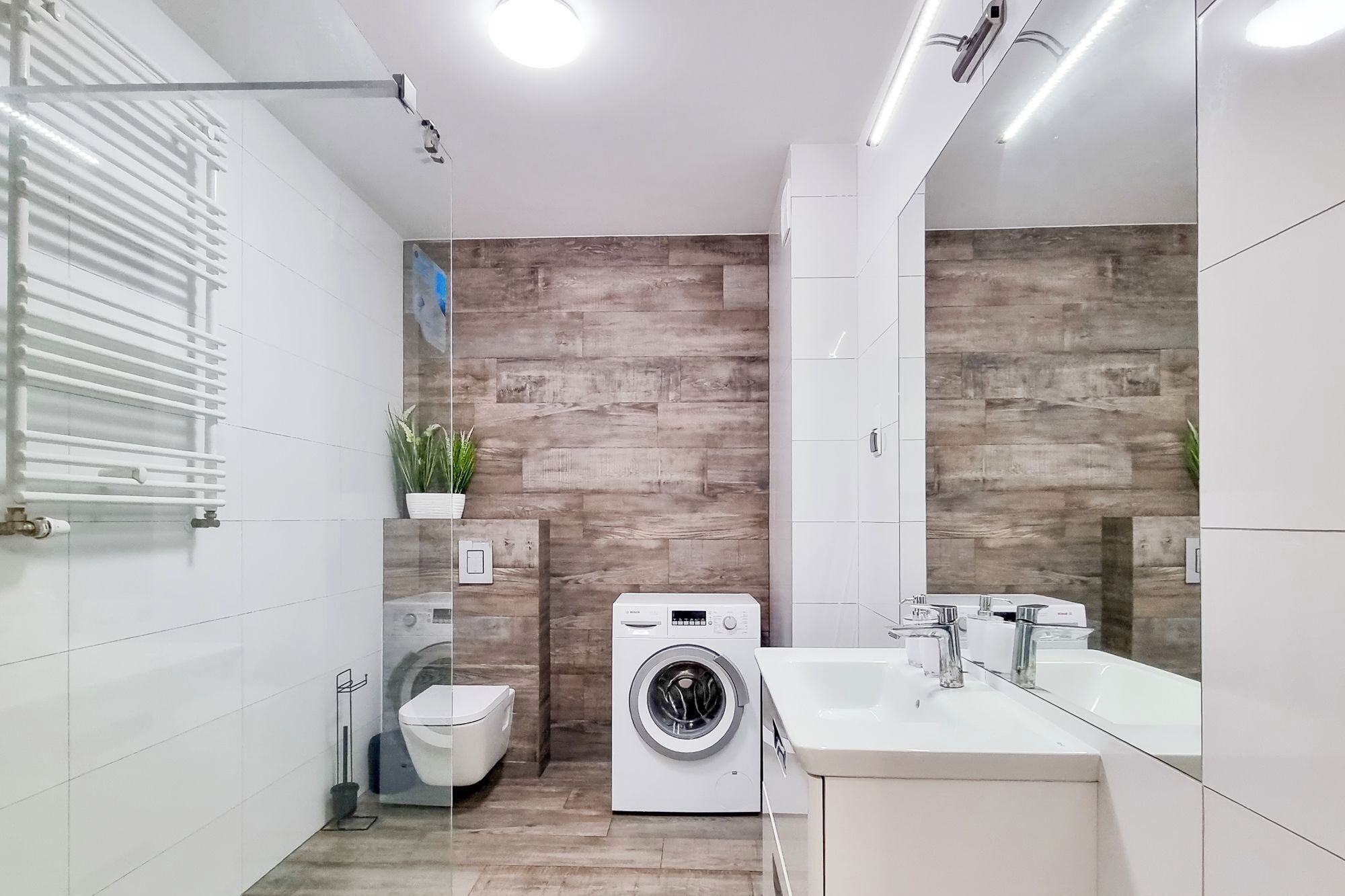A modern bathroom with a washing machine, a toilet, and a sink.