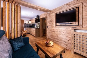 Un intérieur moderne avec un mur en bois, un téléviseur à écran plat, une table à manger agrémentée d’un saladier de fruits et un canapé.