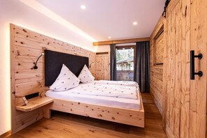 A wooden-paneled bedroom with a bed, bedside tables, and a view of the outdoors.