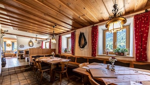 A wooden interior with tables and benches, a chandelier, and a window with curtains. - Gasthof Dürrlehen (Berchtesgaden)