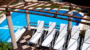 A poolside area with sun loungers and a pergola structure. - Princess Apartman (Siófok)
