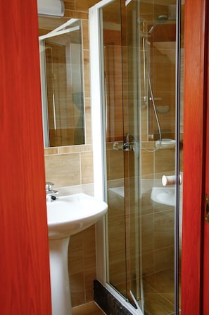 A modern bathroom with a glass shower enclosure, a white sink, and a mirror above it. - Princess Apartman (Siófok)
