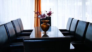 A dining area with a table, chairs, a vase with flowers, and a ceiling light fixture. - Princess Apartman (Siófok)