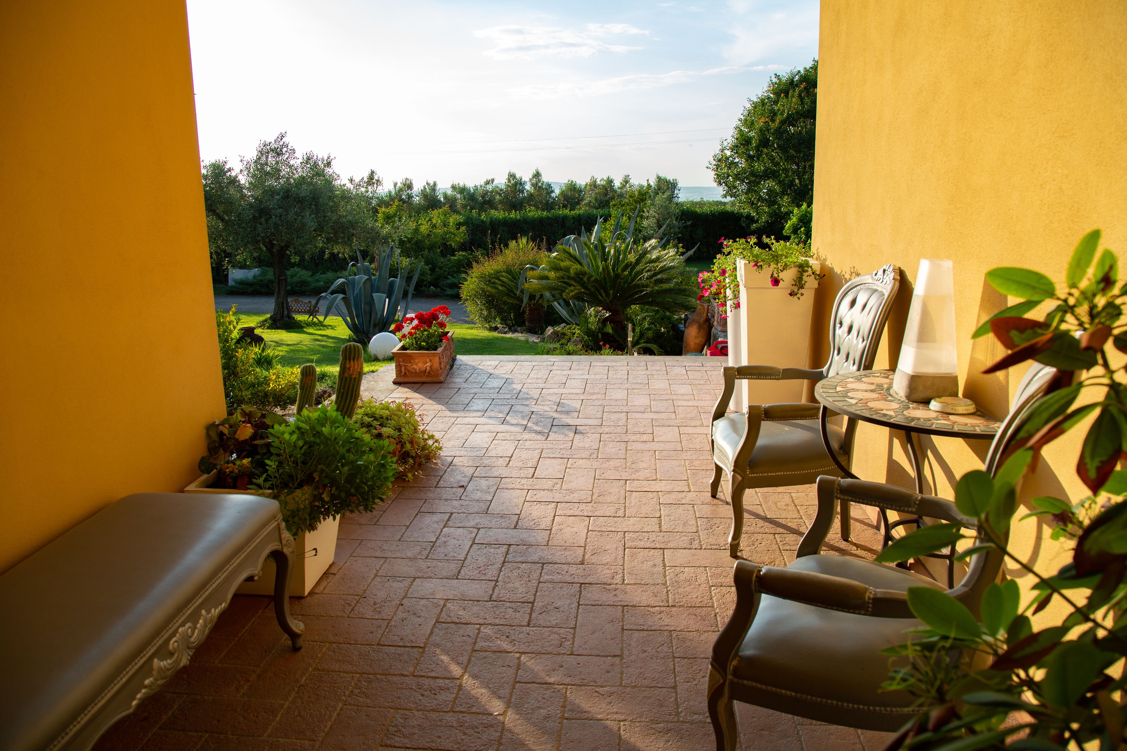 Un patio al aire libre con un banco, sillas y una mesa.