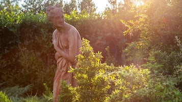 A statue in a garden with dense foliage and sunlight filtering through.
