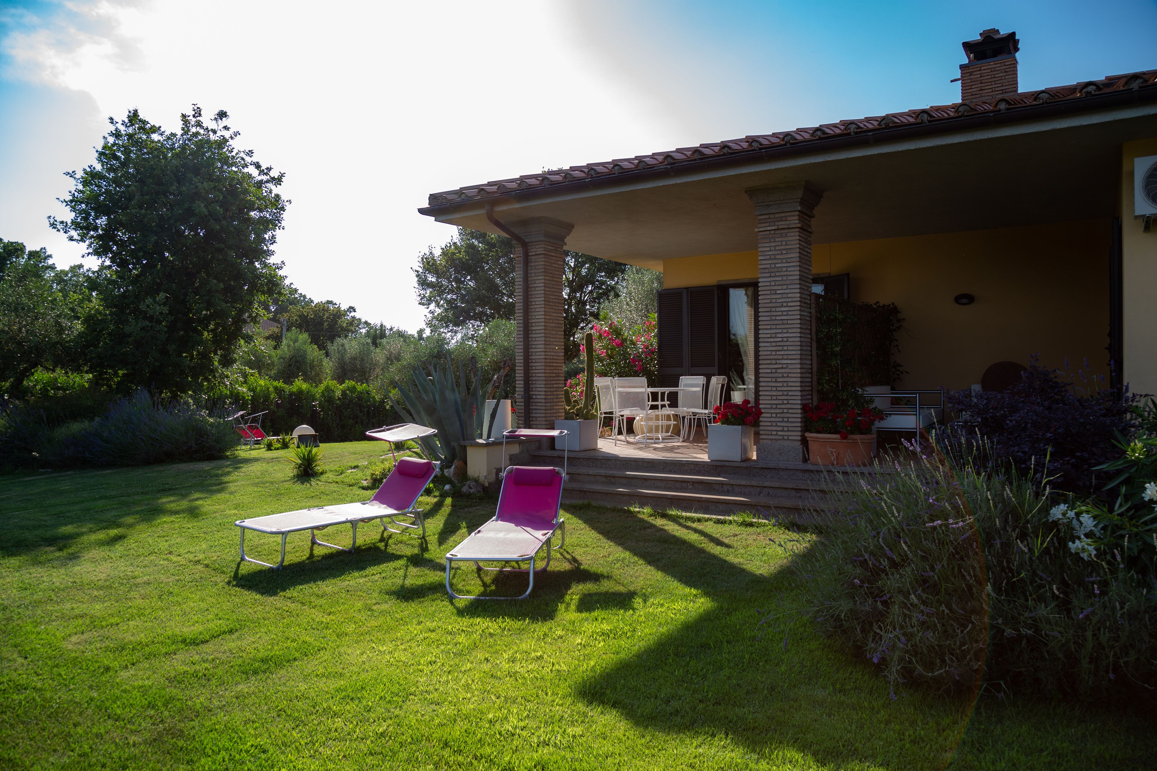 Un patio con dos sillones de descanso, una mesa y una zona de estar cubierta con vistas al jardín.
