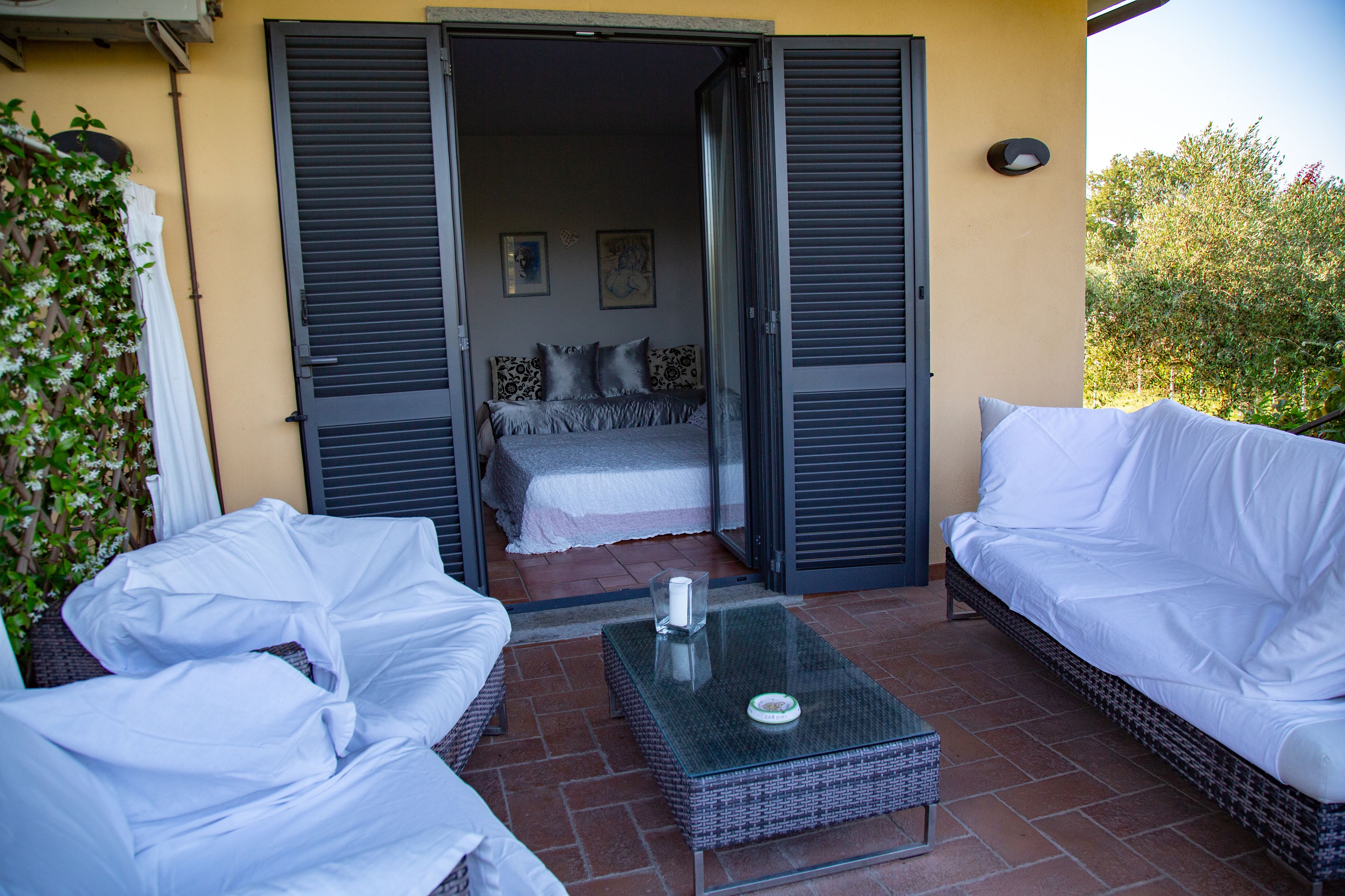 Un balcón con una cama, dos sofás blancos y una mesa de centro de vidrio.