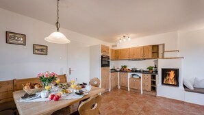 Una cocina moderna con armarios de madera, una mesa de comedor dispuesta para el desayuno y una chimenea.