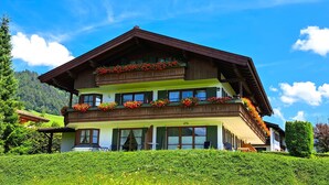 Een meerlaags chalet met bloembalkons, tegen een helderblauwe lucht.